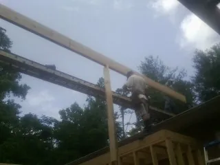 Carpenter setting a ridge beam over a new addition frame — Ice Dam Removal by Roofing Brothers in Scipio