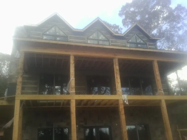 Dormers and porch framing on a large log home under construction — Roof Coating work by our crew in Scipio
