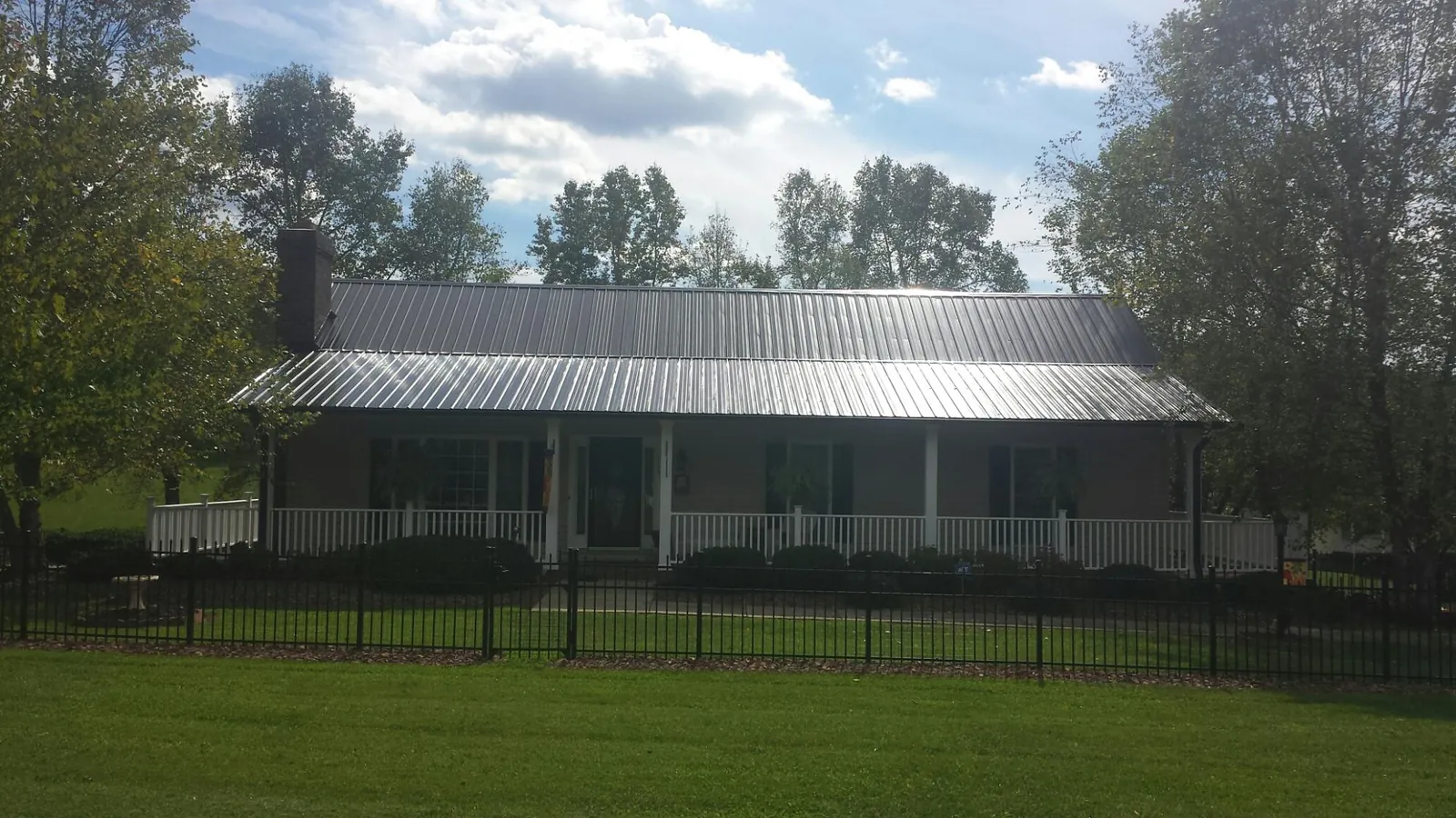 Gray metal roof on a brick ranch with a full width front porch — Gutter Guard Installation work by our crew in Scipio